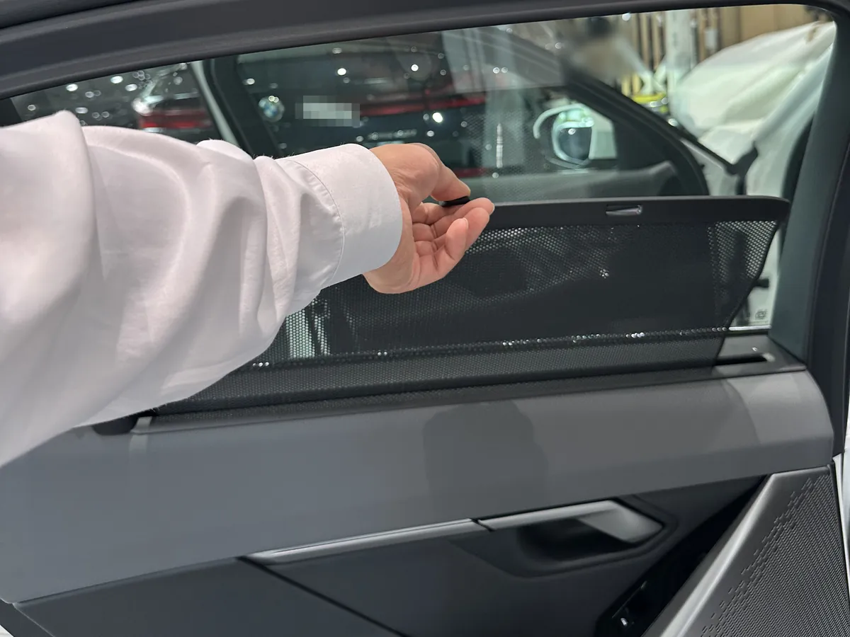 BMW 530i 뒷문 유리의 선블라인드를 손으로 끌어올리는 모습