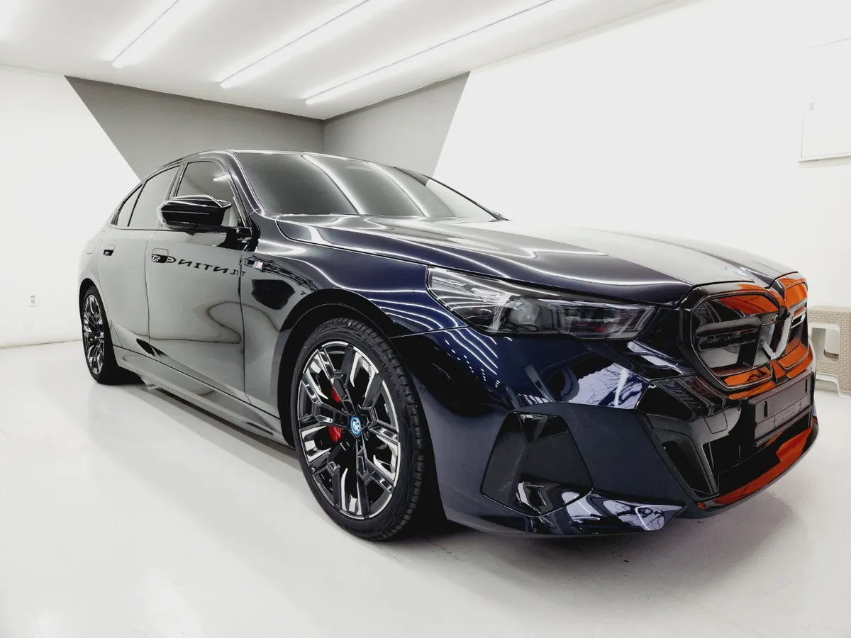 그릴과 앞범퍼를 보호재로 가려 둔 작업 중인 짙은 남색 BMW i5