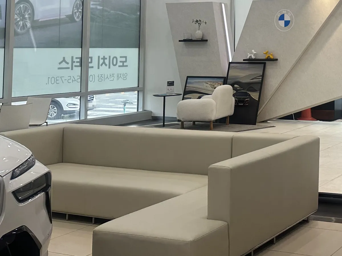 양재전시장 안 소파 라운지 — BMW 로고가 걸린 벽 앞
