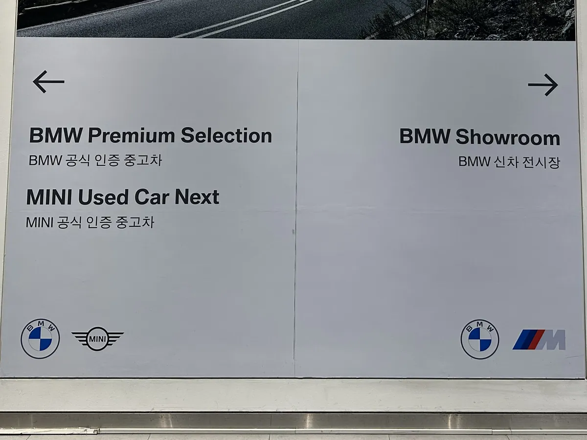 건물 안 안내판 — 왼쪽 BMW 공식 인증 중고차·MINI, 오른쪽 BMW 신차 전시장